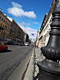 Road by buildings in city against sky