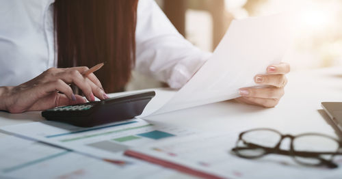 Midsection of woman using smart phone on table