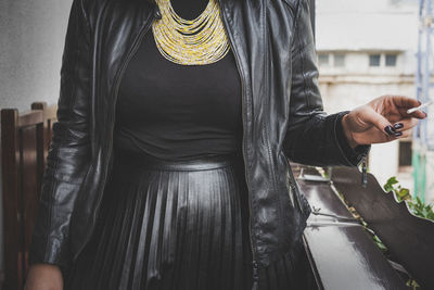 Midsection of woman smoking cigarette at balcony