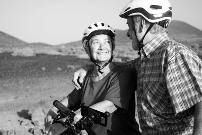 Couple looking at each other while standing with bicycles on land