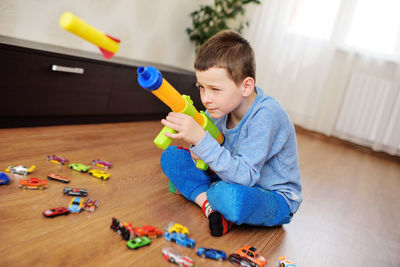 A small hyperactive child preschool boy shoots foam bullets from a toy gun weapon.