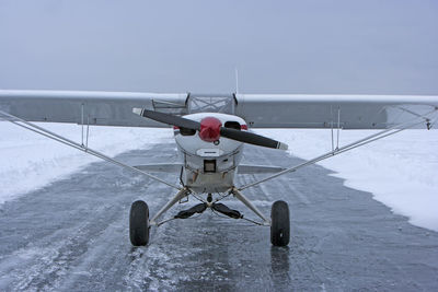 Airplane on runway against sky during winter