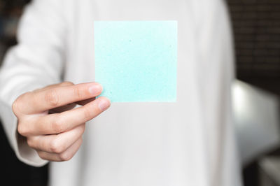 Woman is holding a note with blank space. a woman is holding a square empty blank sticker in her