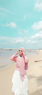 Woman standing on beach against sky