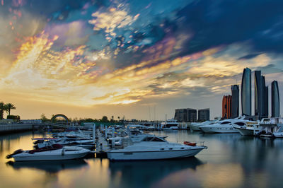 Sailboats moored in harbor against sky during sunset