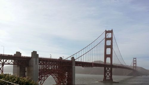 Suspension bridge in city against sky