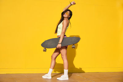 Full length of woman standing on yellow wall