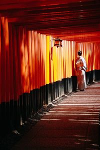 Rear view of woman standing against orange wall