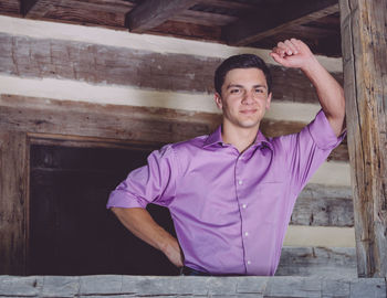 Portrait of smiling young man standing in log cabin