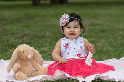 Portrait of cute girl with toy sitting on field