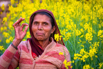 Portrait of woman standing on yellow flowering plants