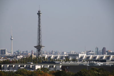 Communications tower in city against clear sky