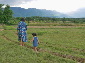 Rear view of women on field against sky