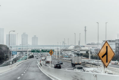 Vehicles on highway against clear sky in foggy weather