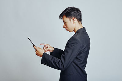 Side view of young man using smart phone against white background