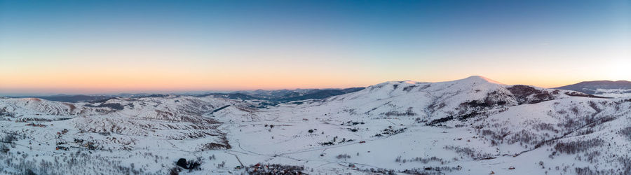 Scenic view of snowcapped mountains against clear sky during winter