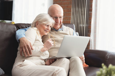Senior man and woman looking at laptop while sitting at home
