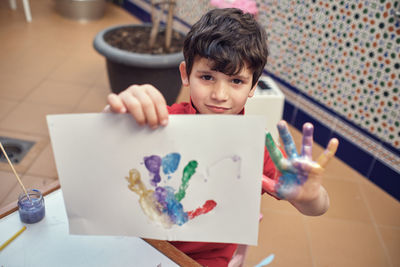 High angle portrait of boy holding baby at home