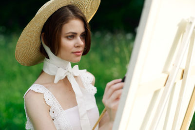 Portrait of bride wearing hat standing outdoors