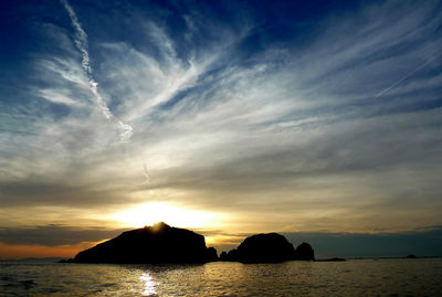 Silhouette rocks by sea against sky during sunset