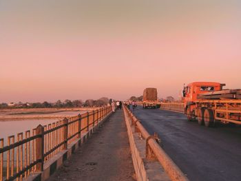 Road by city against clear sky during sunset