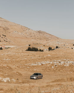 Car on desert against clear sky