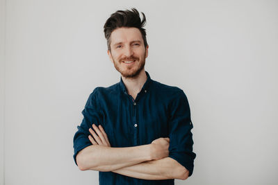 Handsome young man in a dark blue shirt by a light wall. place for text. high quality photo