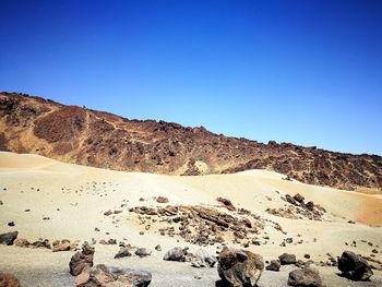 Scenic view of desert against clear blue sky