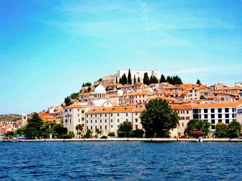 Buildings by sea against sky