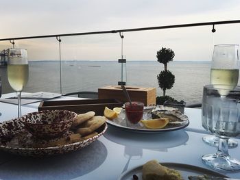 Close-up of food on table at restaurant by sea against sky during sunset