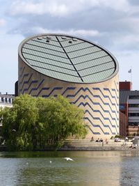 Modern building by river against sky