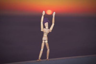 Close-up of wooden figurine against sunset