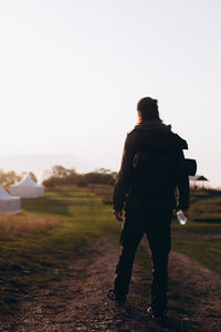 Rear view of man standing on field against clear sky