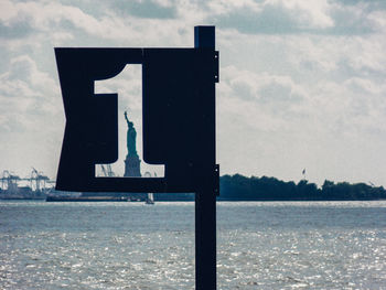 Information sign by sea against sky