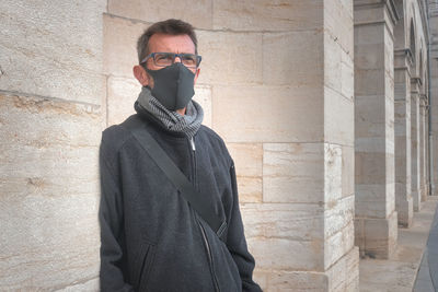 Man wearing sunglasses standing against wall