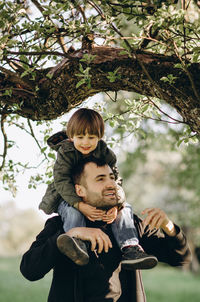 Father and son on plant against trees