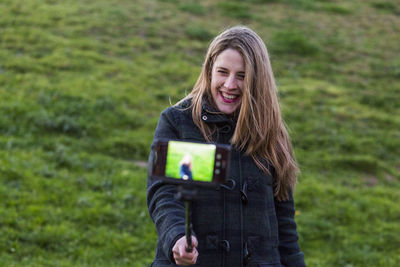 Portrait of smiling woman holding smart phone outdoors