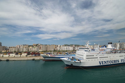 Boats moored in sea against buildings in city