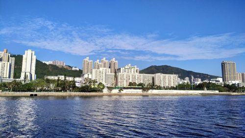 Buildings by lake against blue sky