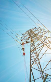 Low angle view of electricity pylon against blue sky