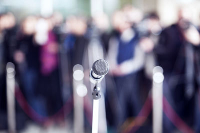 Close-up of microphone with people standing in background