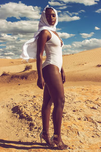 Side view of woman standing on sand at desert