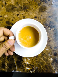 Cropped image of person holding coffee cup on field