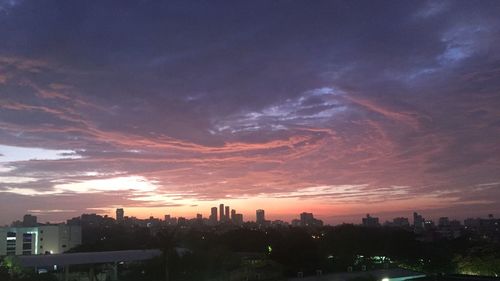 Buildings in city against romantic sky at sunset