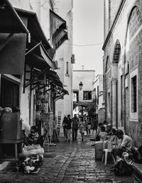 People walking on alley amidst buildings in city