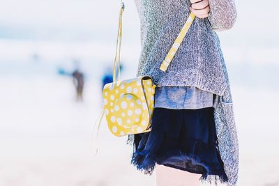 Midsection of woman standing with yellow purse