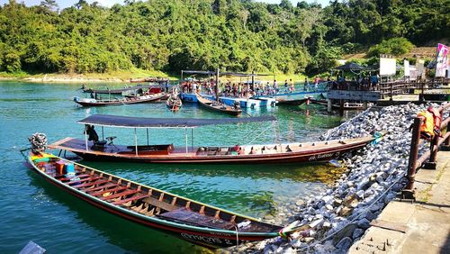 Boats moored on river by trees