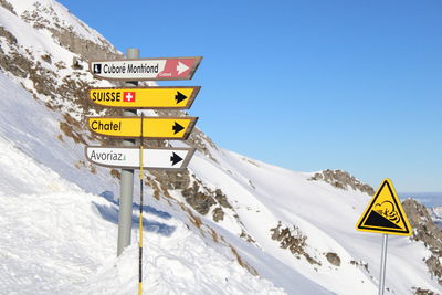 Low angle view of road sign against clear blue sky