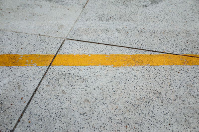 High angle view of yellow road marking on tiled floor