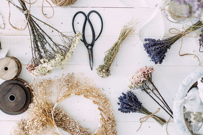 Dry compositions and bouquets of flowers and plants for the interior lie on a white wooden table.